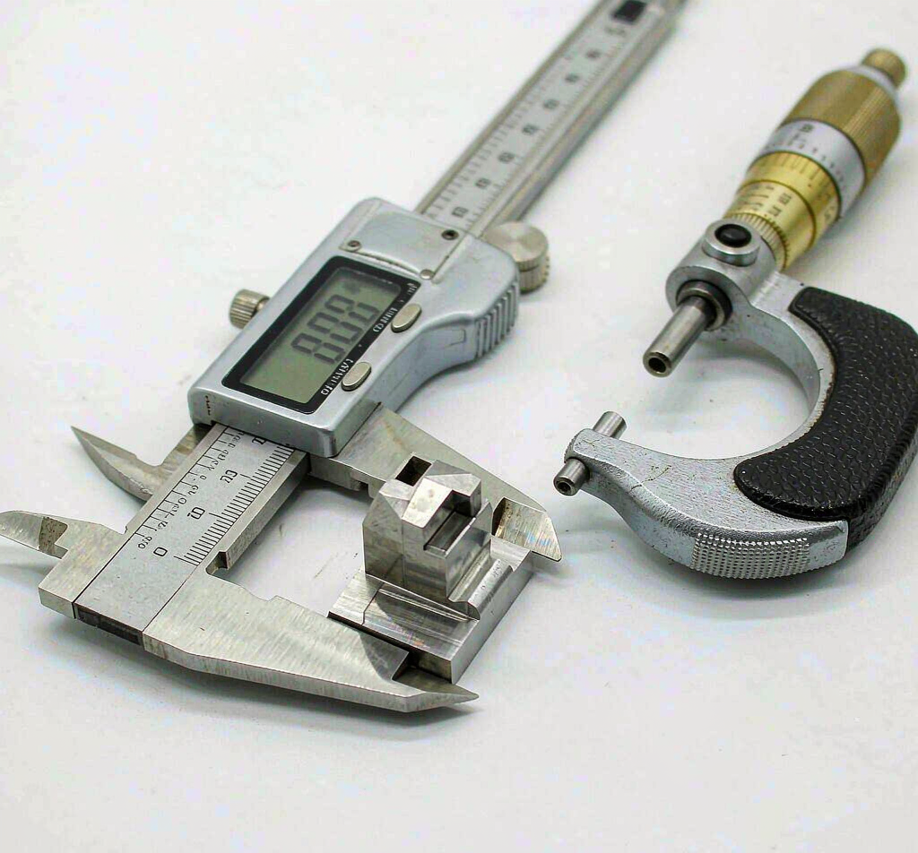 Precision calipers and micrometer measuring a CNC machined part