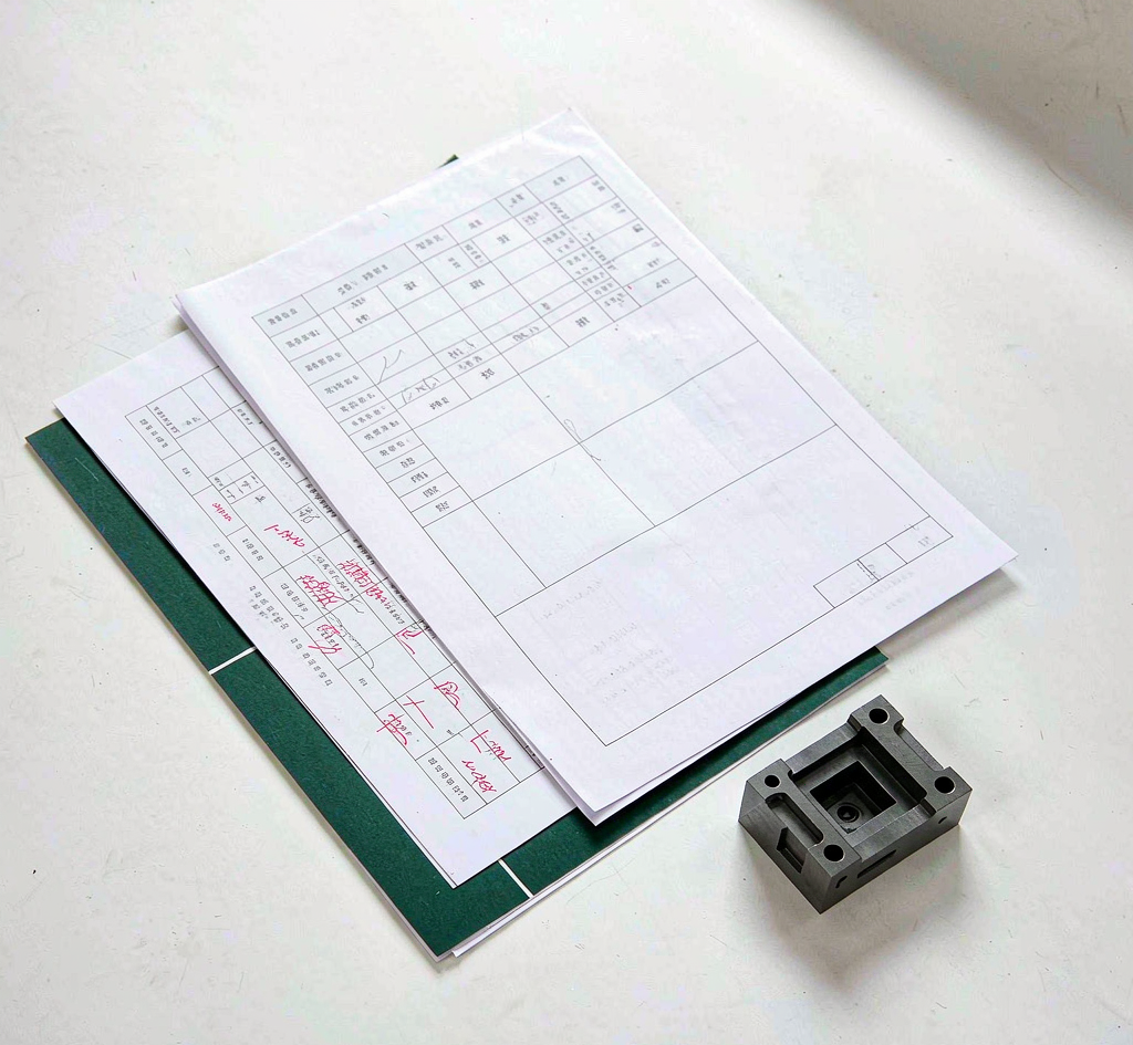 Manufacturing quality documents and a machined part on a desk