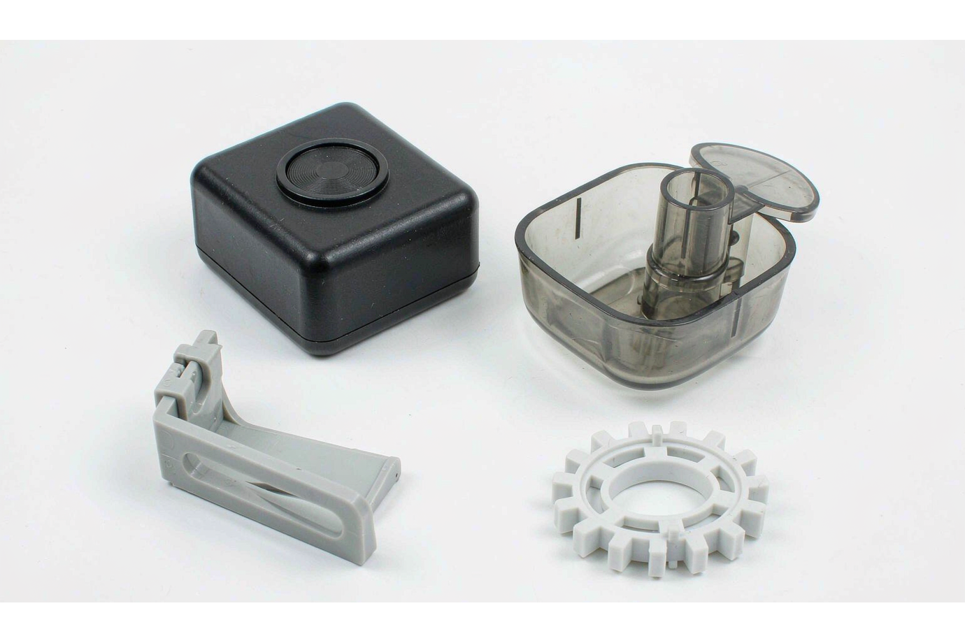 Assortment of custom ABS plastic components: matte black housing, translucent enclosure, gray mounting bracket and white molded gear
