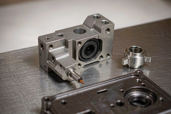 Precision machined aircraft components including a bracket, housing and stainless steel fitting on a workbench