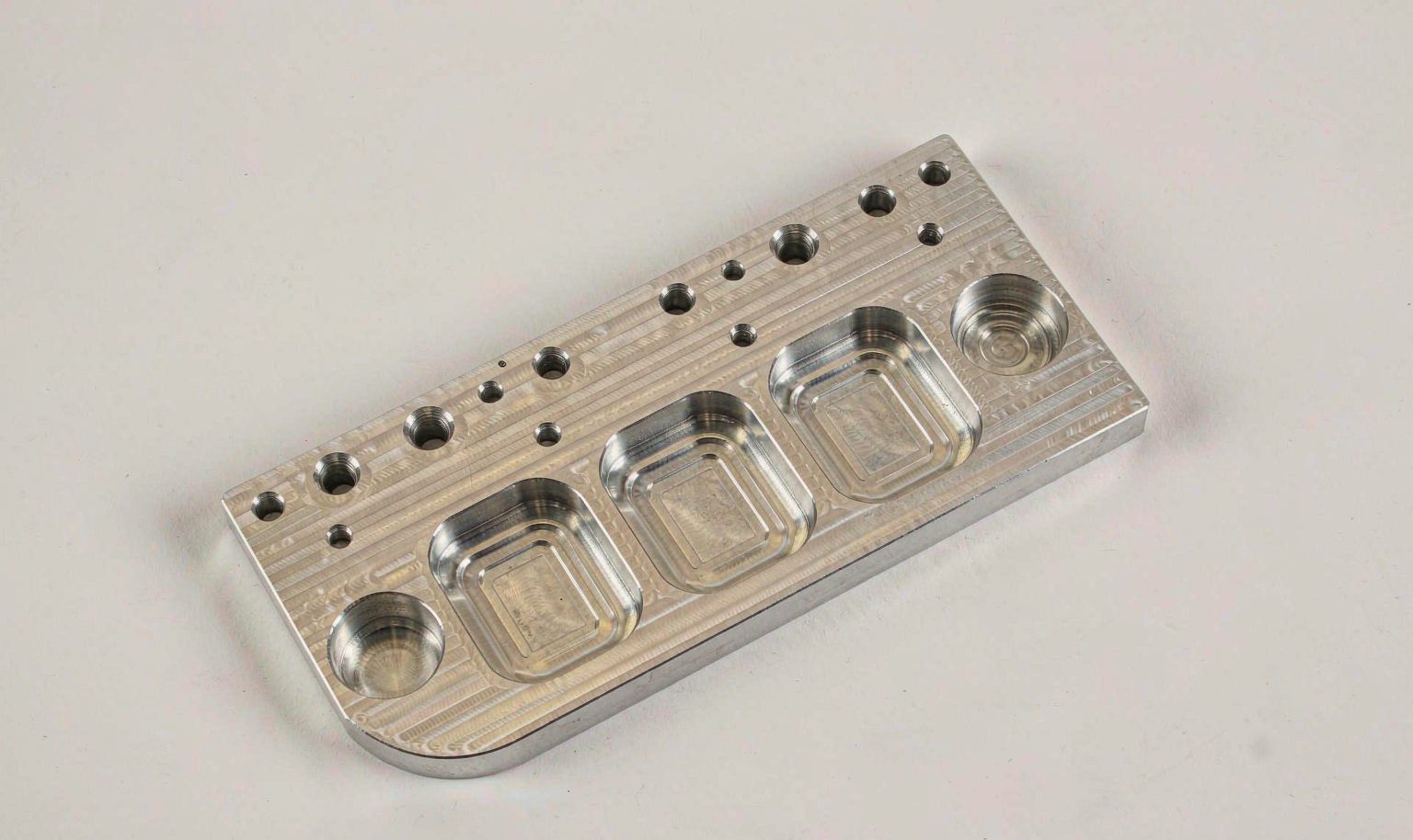 Top-down view of a milled aluminum bracket with pockets and threaded holes