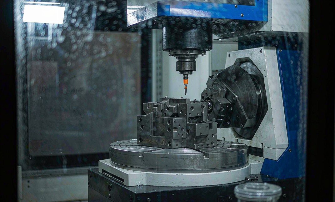 5-axis CNC machining center with a rotary table machining a complex metal component