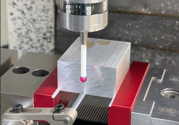 Machined metal workpiece with tooling set up on a CNC machine bed