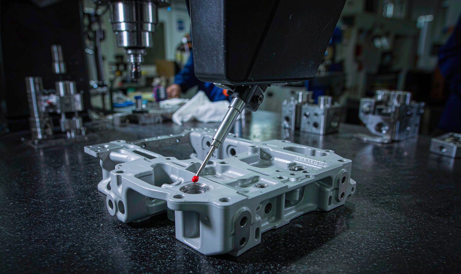 A coordinate measuring machine probing a precision milled aluminum bracket on a granite table