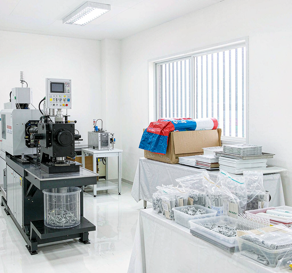 Clean, well-lit controlled production area with injection molding equipment and organized handling of medical plastic components