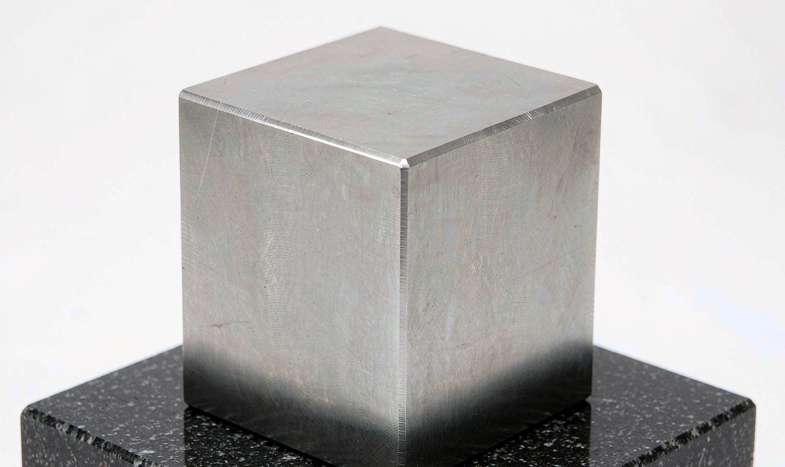 A precisely machined aluminum cubic block on a granite surface plate
