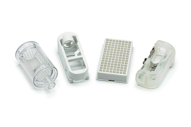 Assortment of custom medical plastic injection molded components including device housings, connectors and single-use parts on a clean white surface
