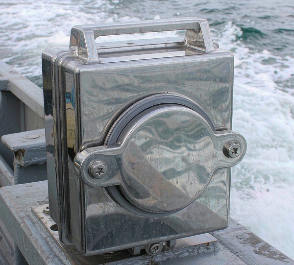 Stainless steel junction box on a boat deck near water on an overcast day