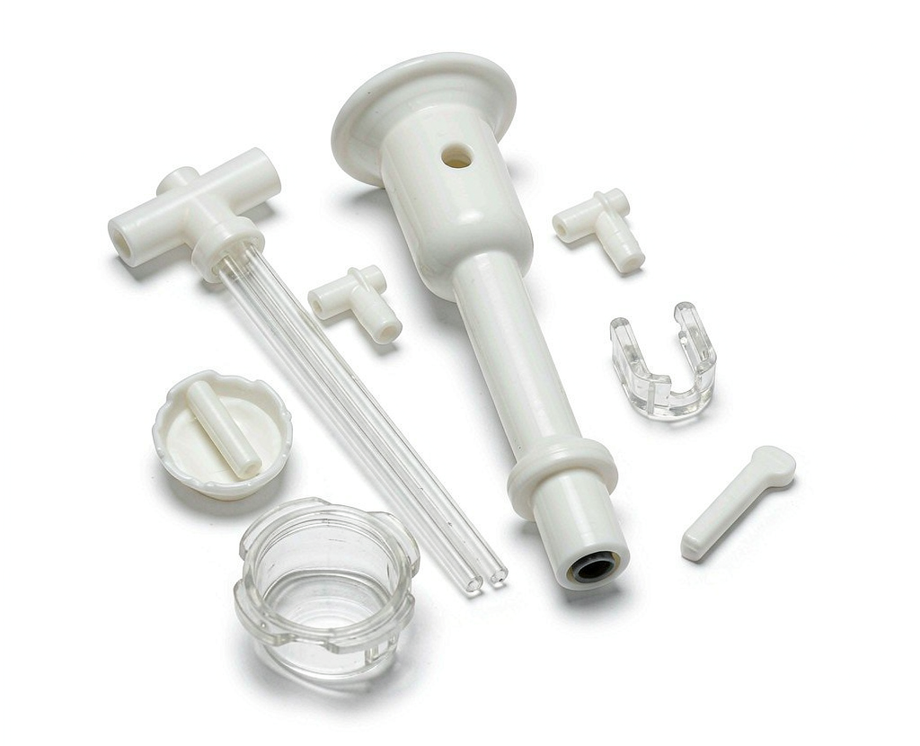 Grouping of moulded and machined medical plastic components showing housings, connectors and precision parts