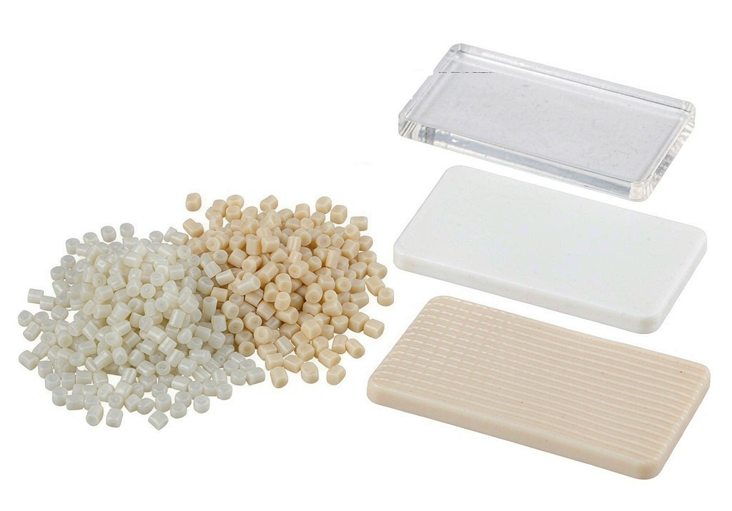 Selection of medical-grade polymer resin pellets and moulded sample plaques arranged for material comparison