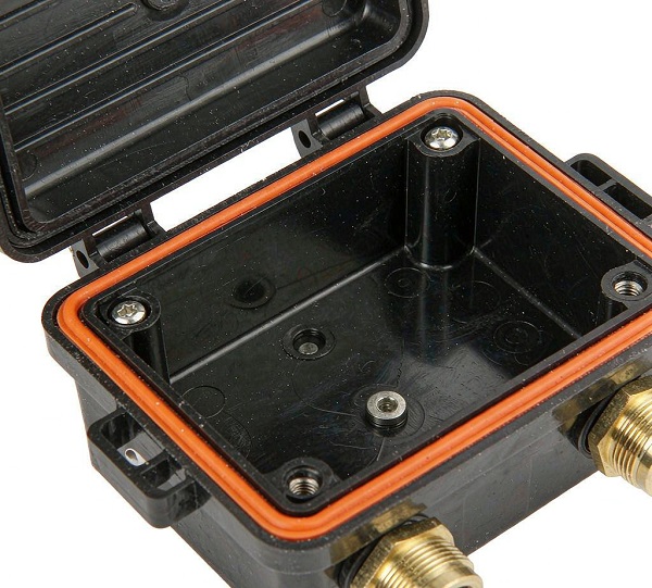 Open IP68 junction box lid showing orange silicone gasket groove, brass glands and molded mounting bosses