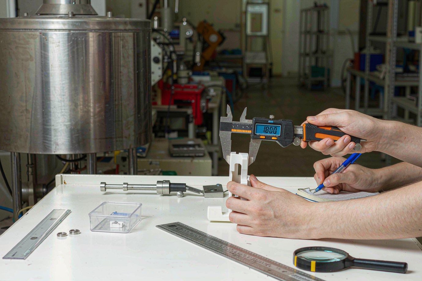 Technician measuring a white molded plastic part with a digital caliper during inspection