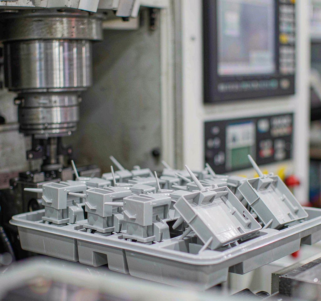 First-trial T1 injection molded plastic sample parts with sprues and runners in a grey tray aligned for inspection