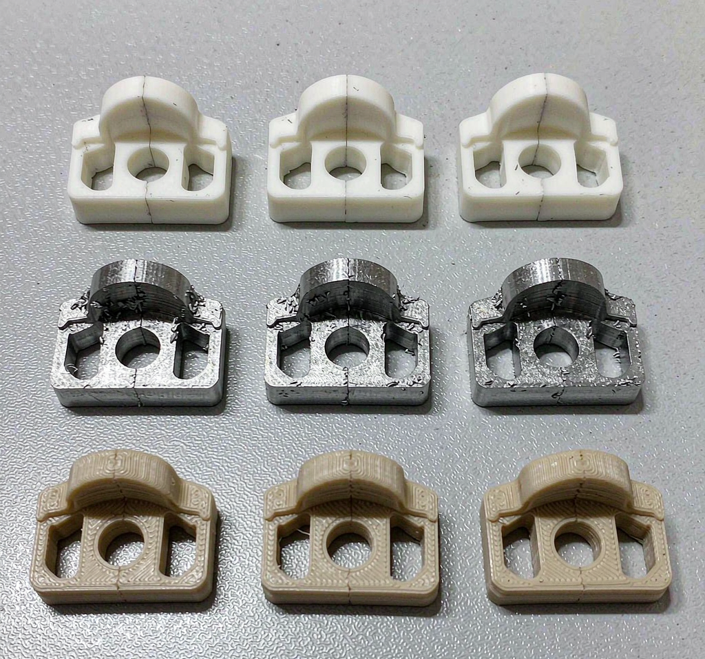 Comparison of the same plastic bracket part made by injection molding, CNC machining and 3D printing, arranged in three rows on a grey workbench