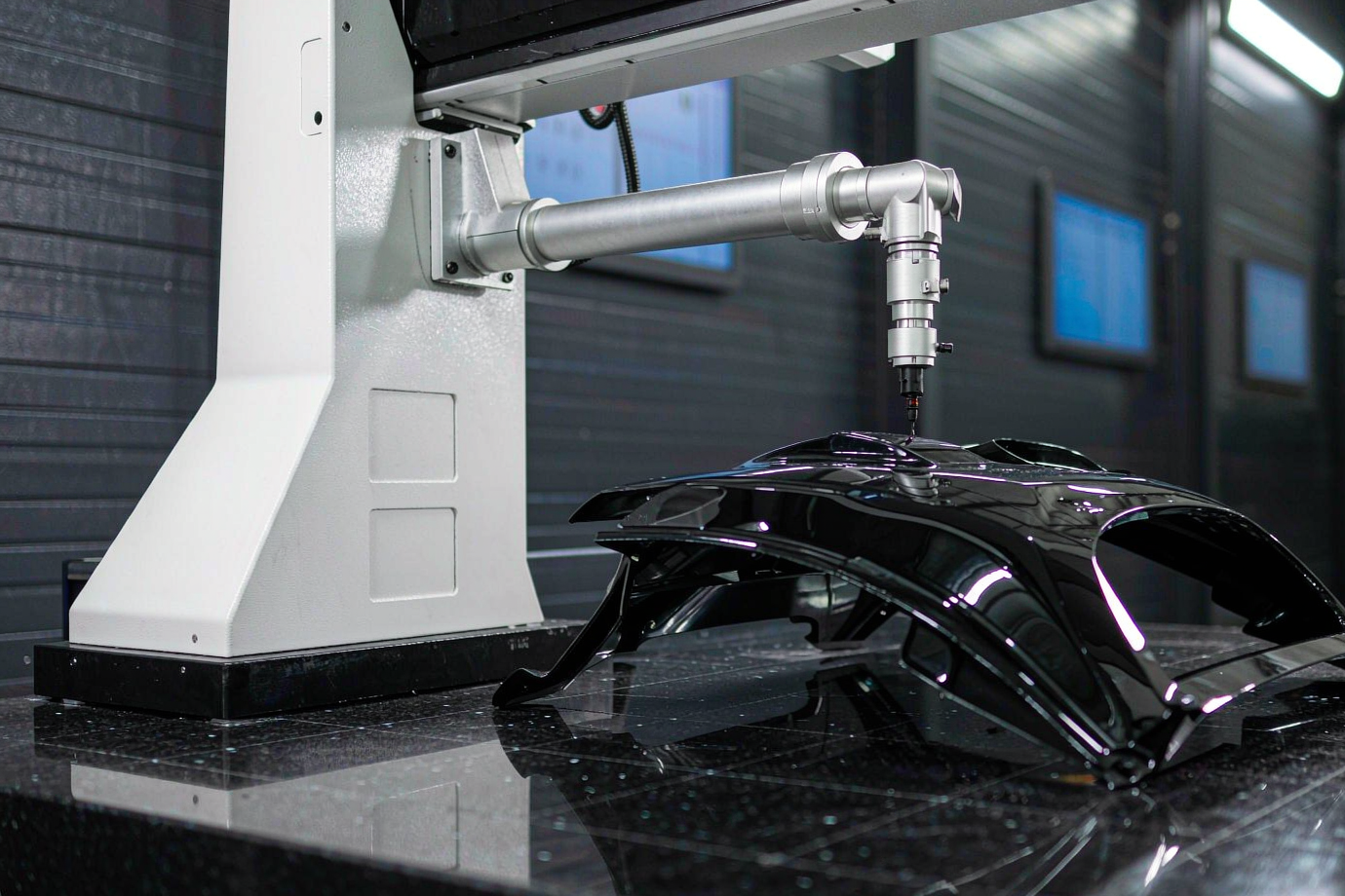 Coordinate measuring machine inspecting an automotive spoiler component on a granite table