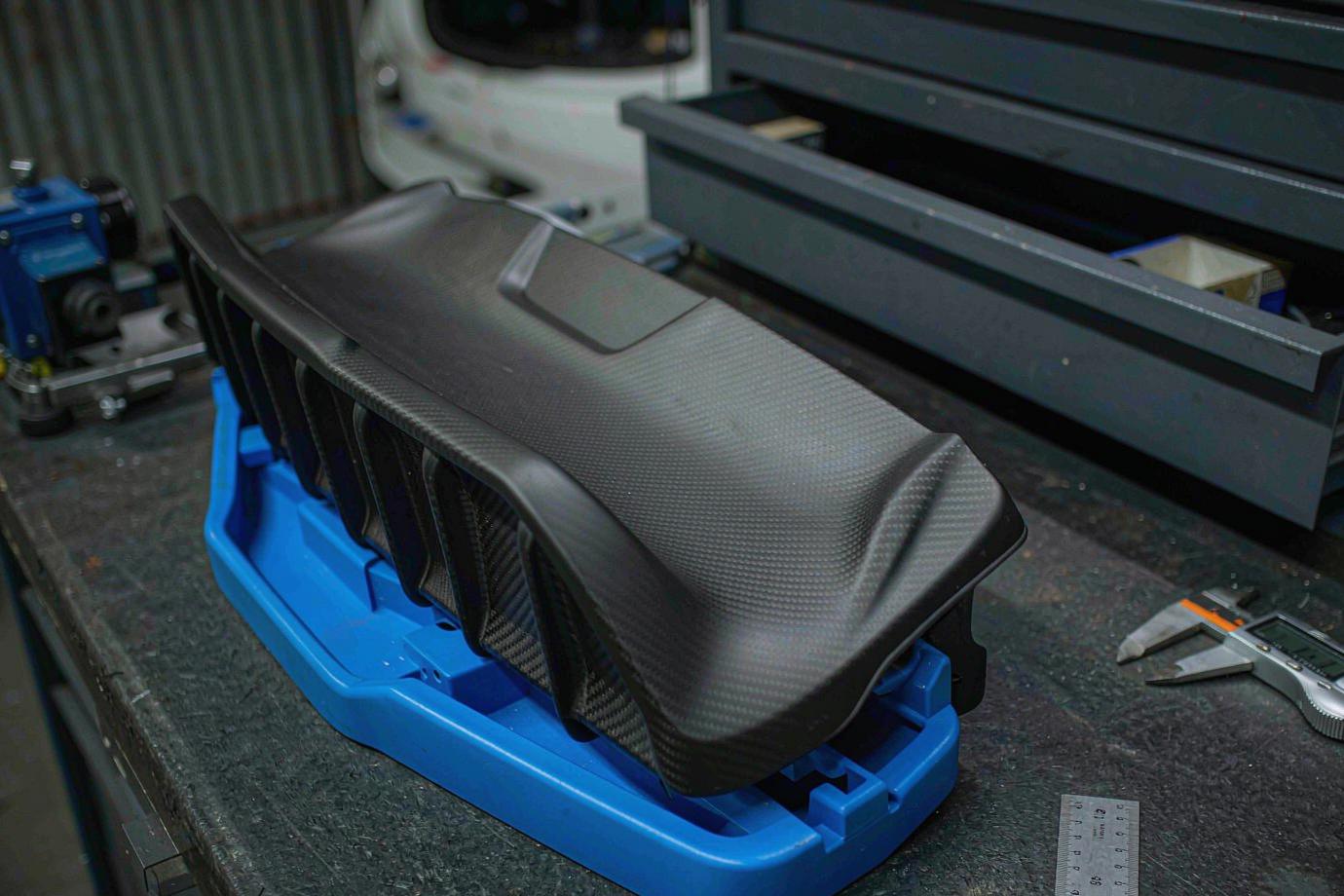 Automotive rear wing spoiler dry-fitted against a car trunk with alignment gauges