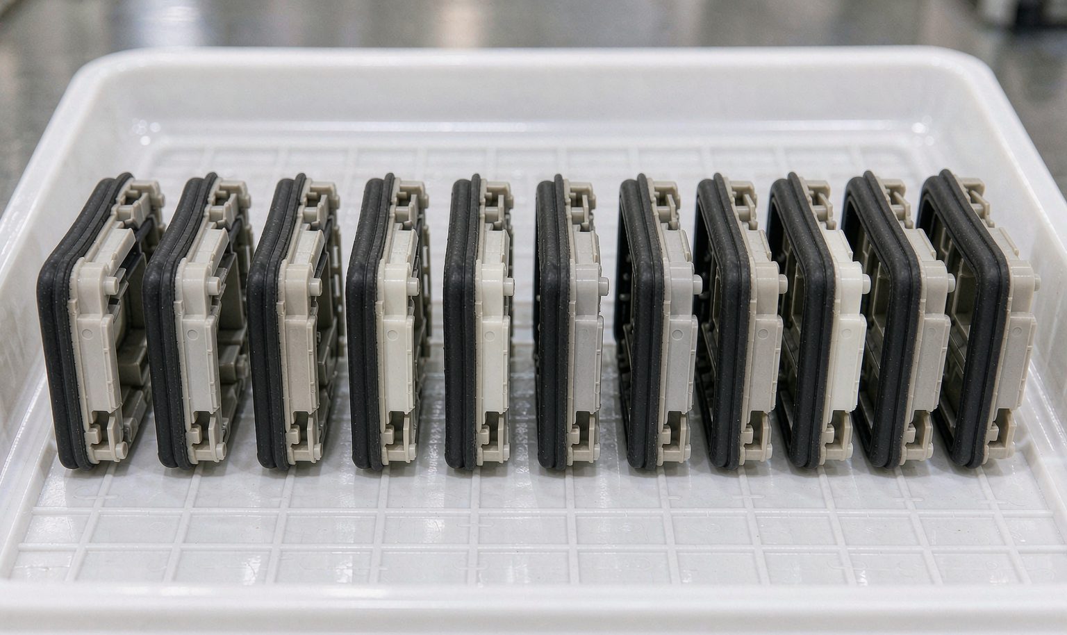 A row of identical two-shot molded multi-material parts on an inspection tray