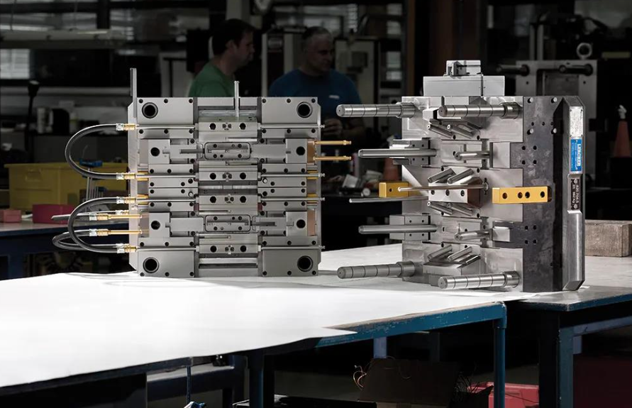 Precision injection mould on a workbench in the Xiamen Goldcattle toolroom with CNC machines behind