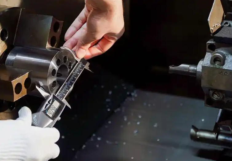 Manufacturing engineer inspecting a machined part with calipers while reviewing a checklist in a workshop