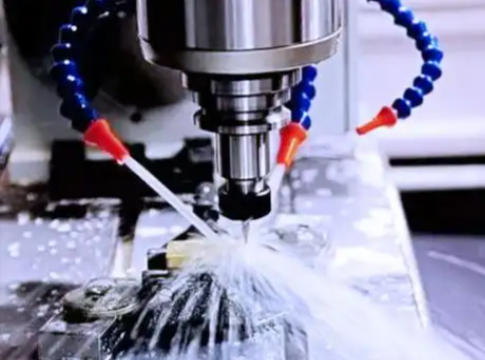 Flood coolant directed through a nozzle at a CNC milling cutter at the cutting zone