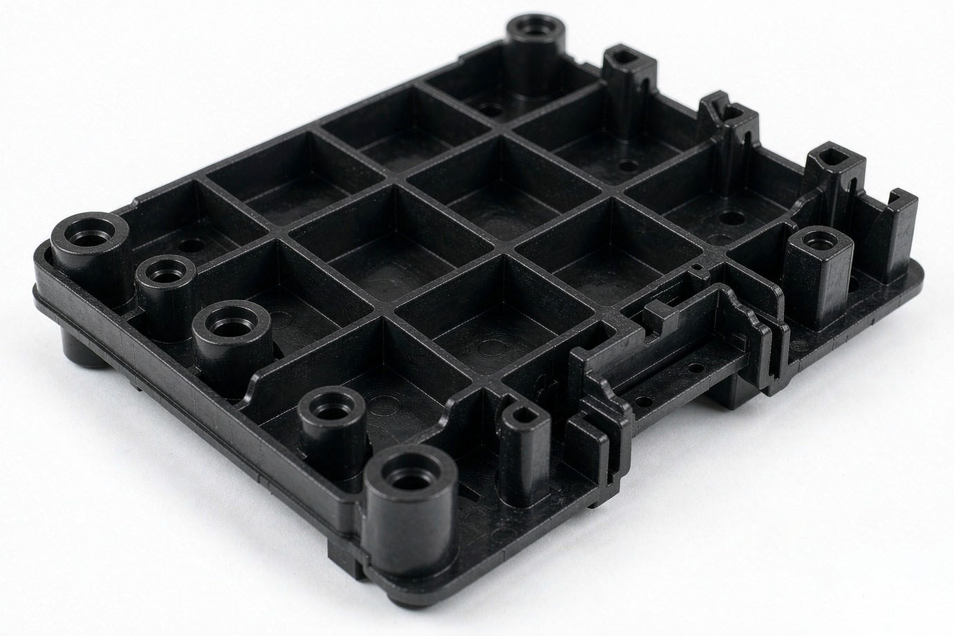 Illustrative — close-up of an injection-molded black plastic part showing precision mounting holes, reinforcing ribs and a molded interface