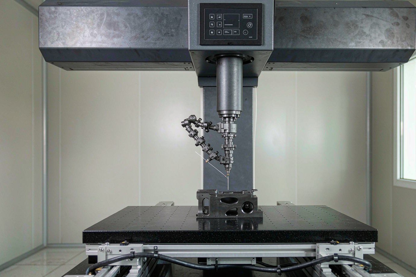 Coordinate measuring machine probe inspecting a finished machined metal part on a granite table