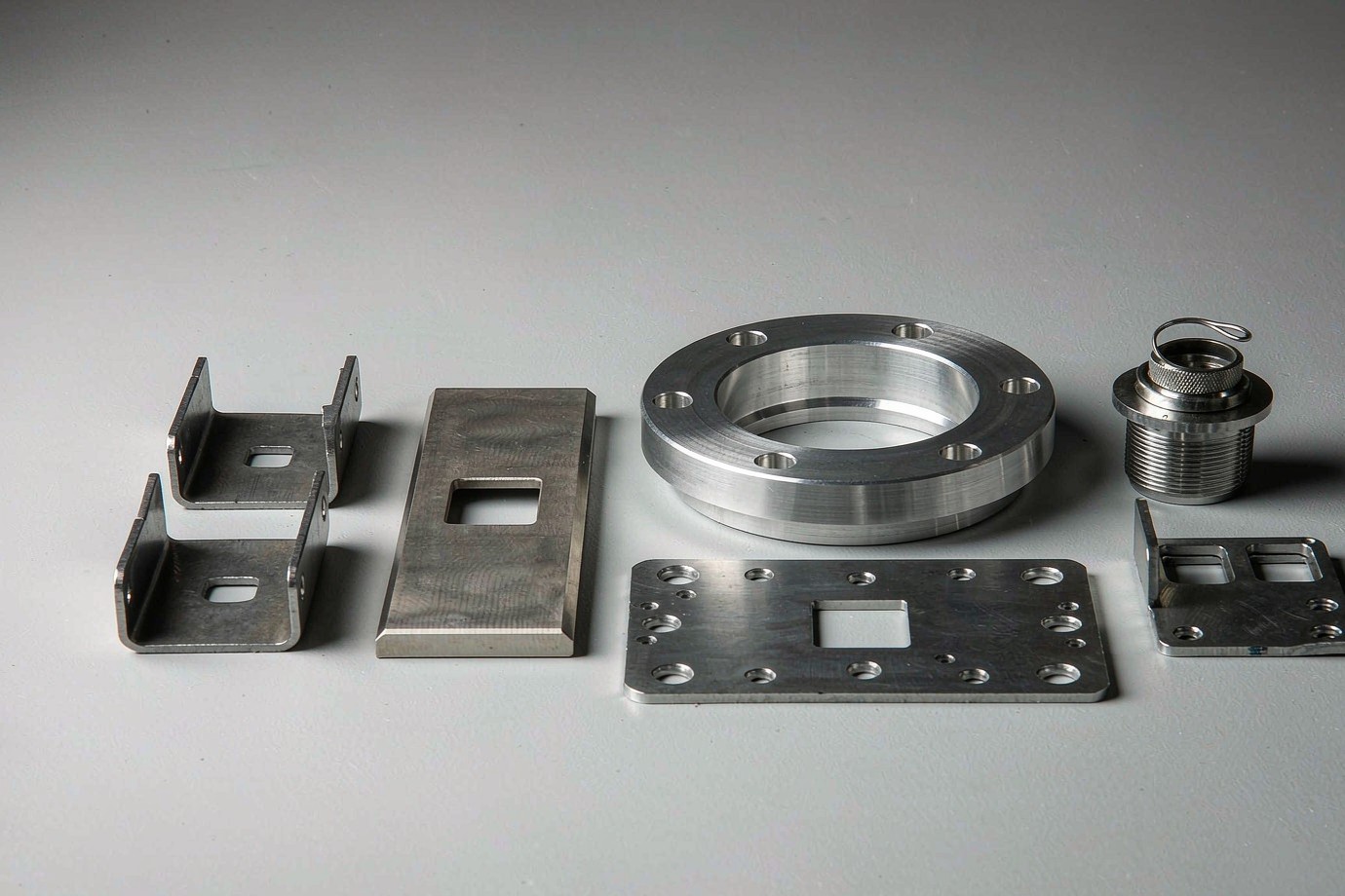 Assorted fabricated metal components for fuel-tank applications: brackets, flanges, fittings and a mounting plate