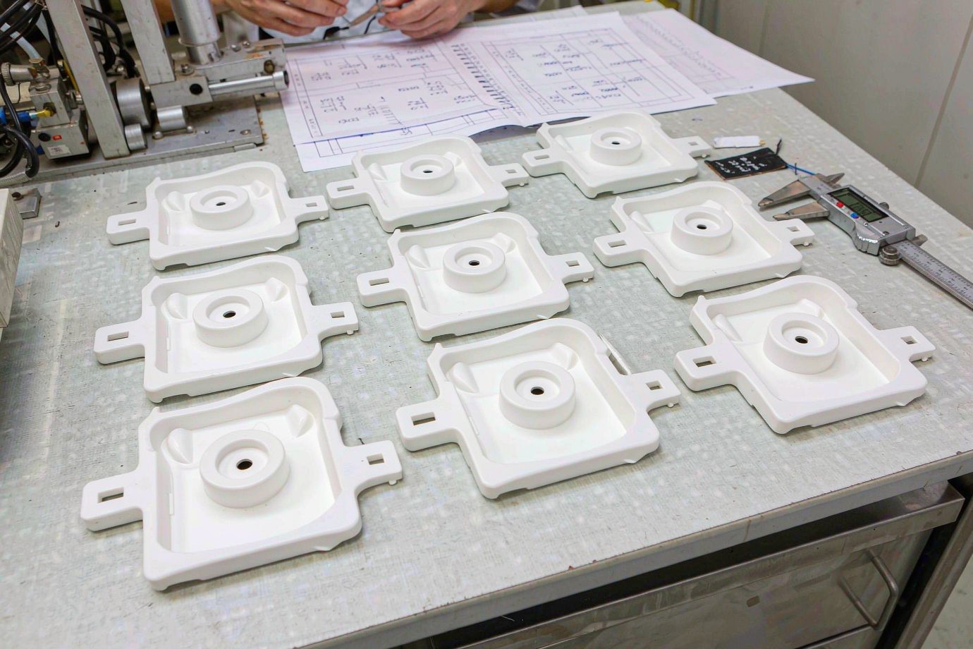 Illustrative dimensional inspection of molded appliance parts with a caliper against a drawing