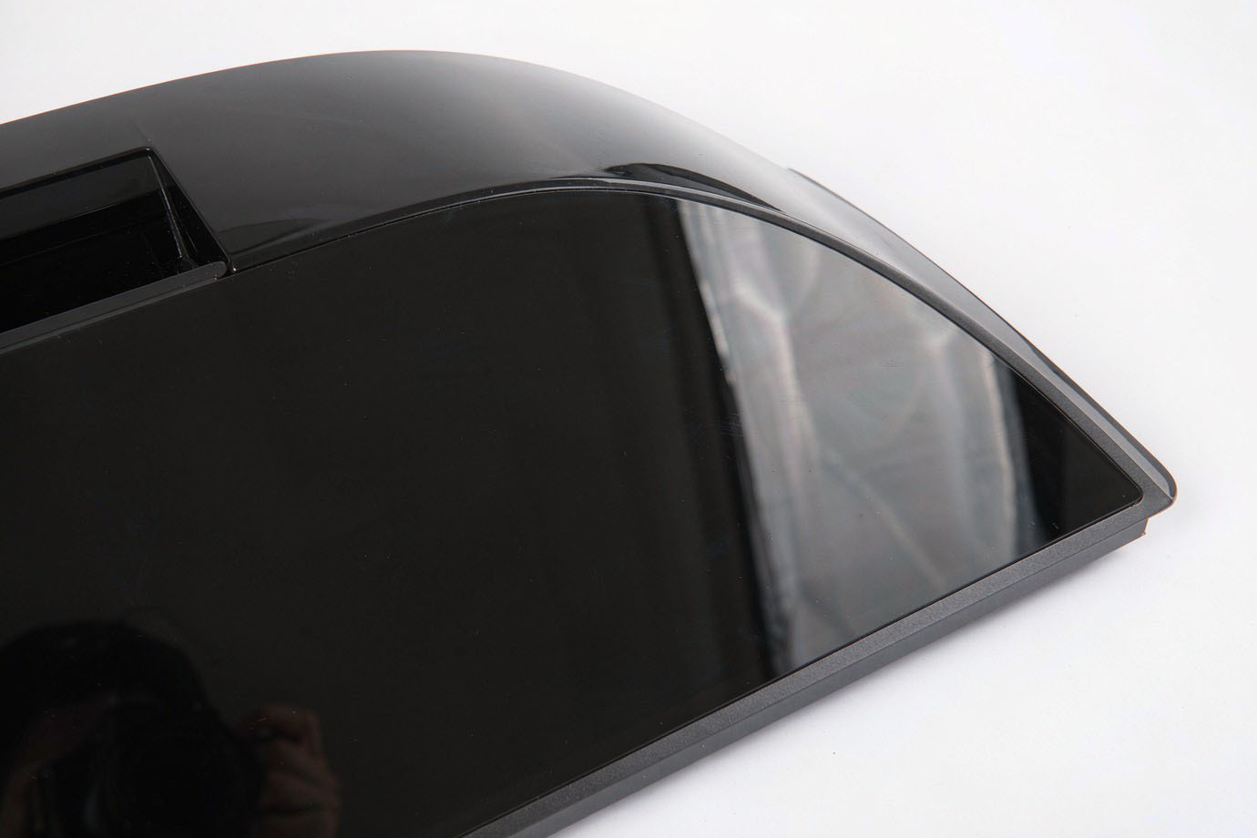 Illustrative — high-gloss black appliance control panel with a flawless mirror finish reflecting studio light