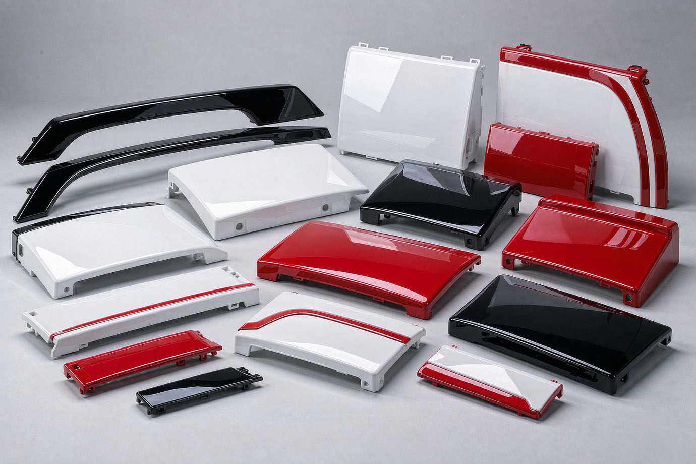 Illustrative — arranged glossy injection-molded appliance panels and bezels in black, white and red with mirror surfaces