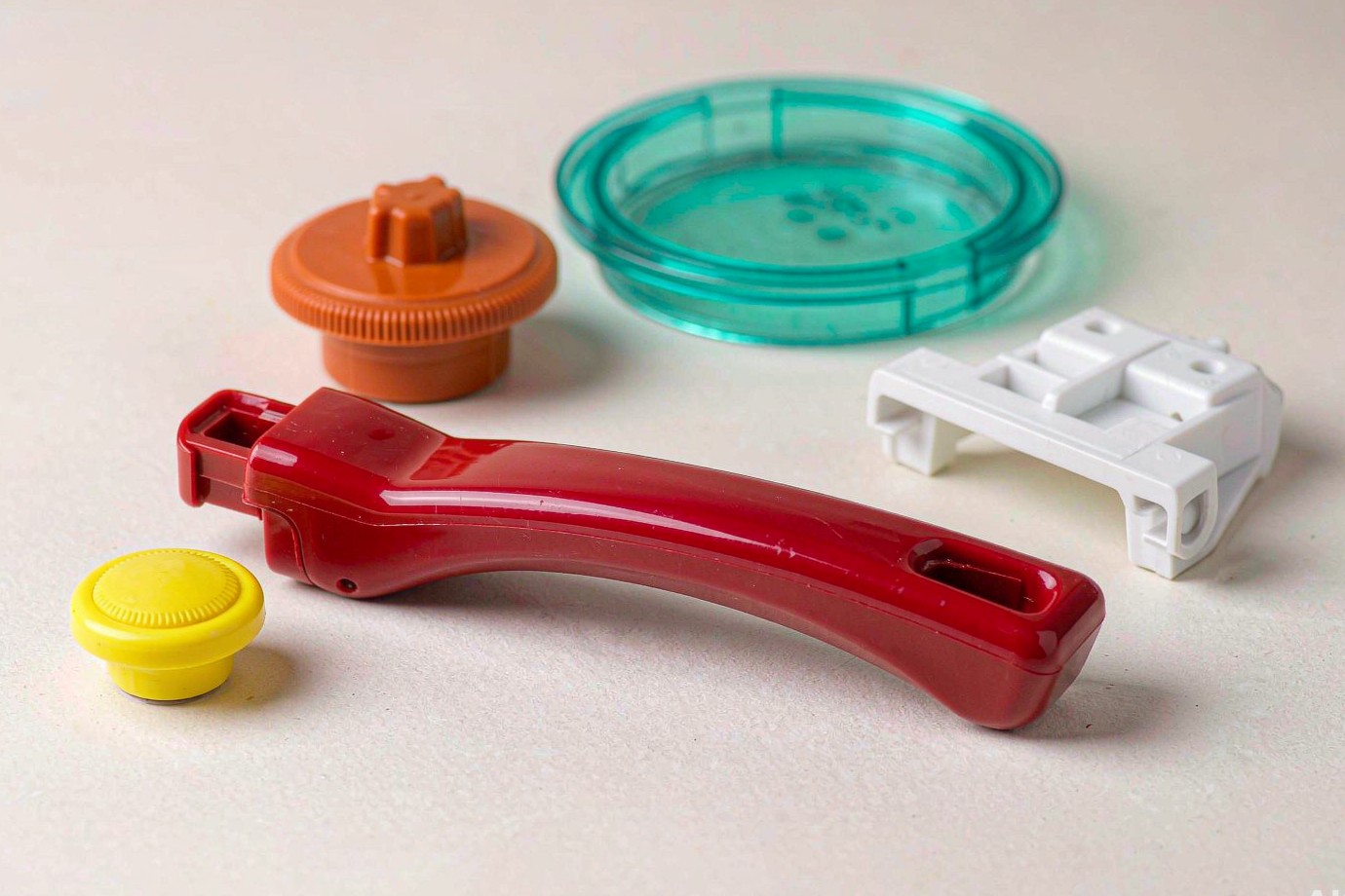 Brightly colored molded kitchen and household components including a handle, knob and lid shown as sample parts (Illustrative)