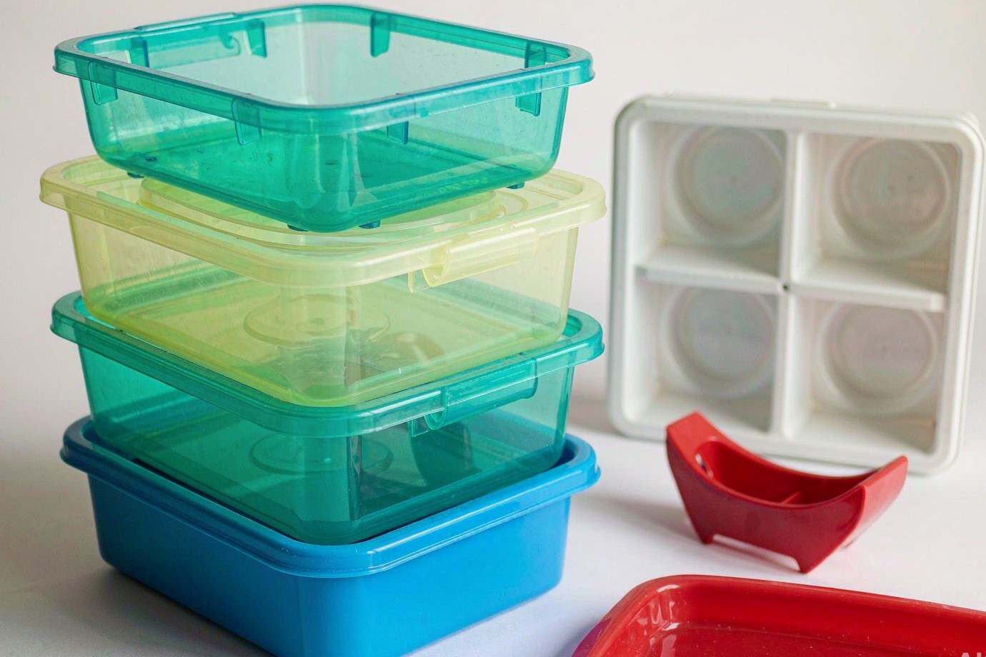 Molded plastic storage bins, trays and a clip arranged as sample household organization components (Illustrative)
