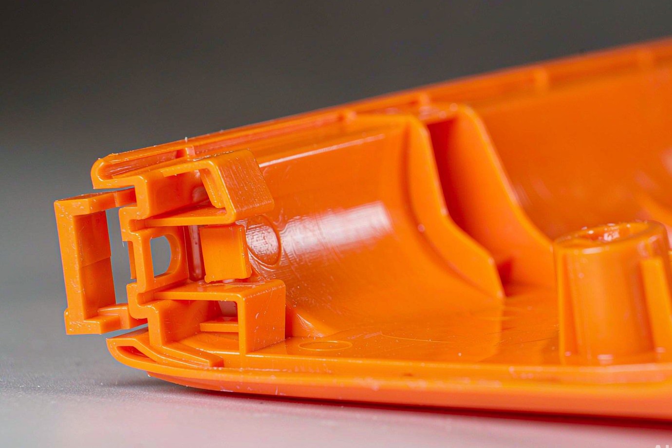 Macro view of an injection-molded part showing a snap-fit clip, ribs and a screw boss as structural design features (Illustrative)