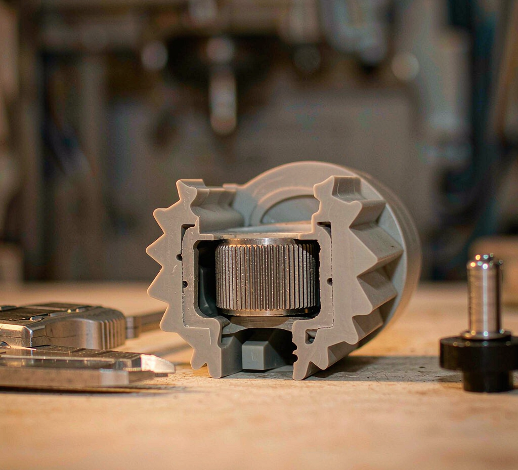 Cutaway insert-molded part showing a knurled metal insert with retention structure beside calipers