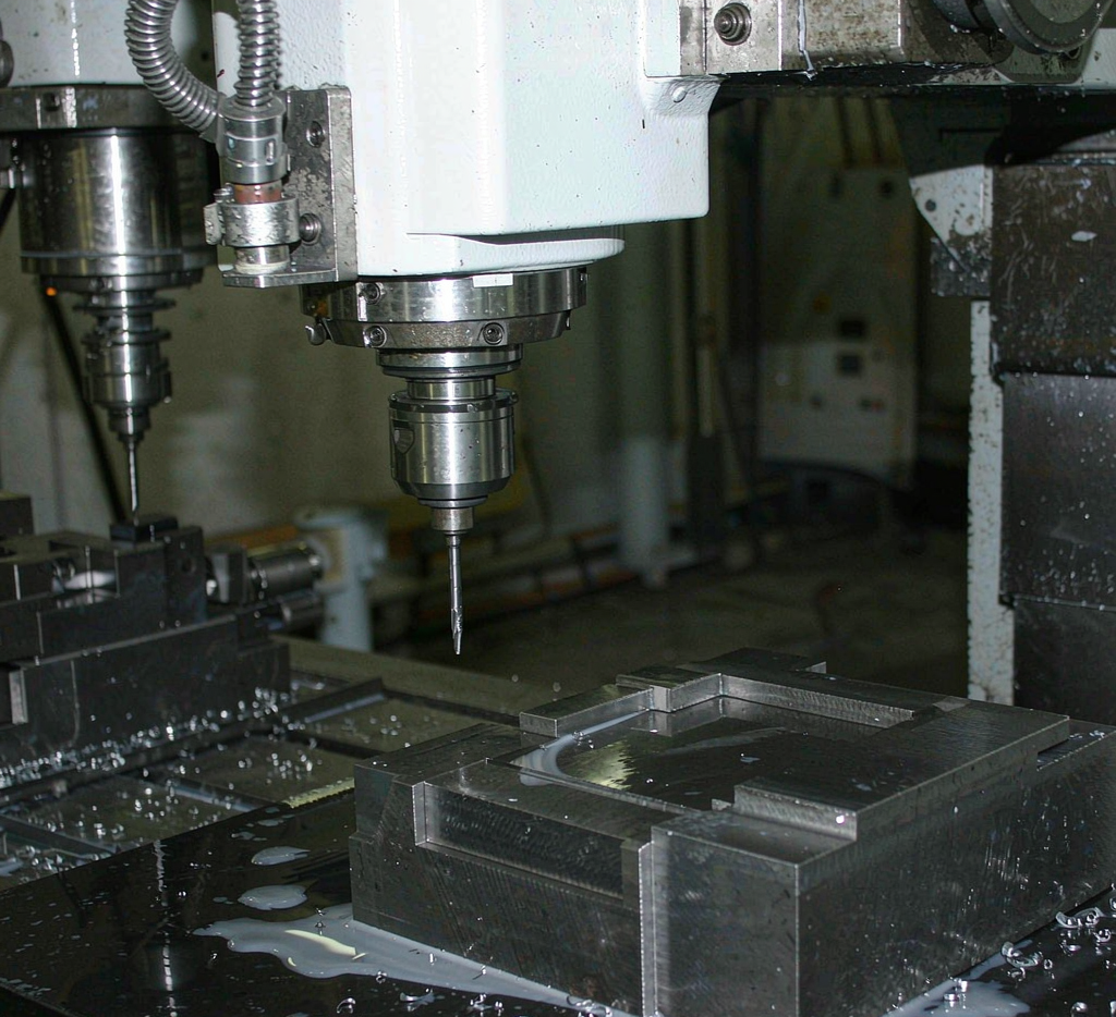 CNC machining center milling a metal component with cutting fluid
