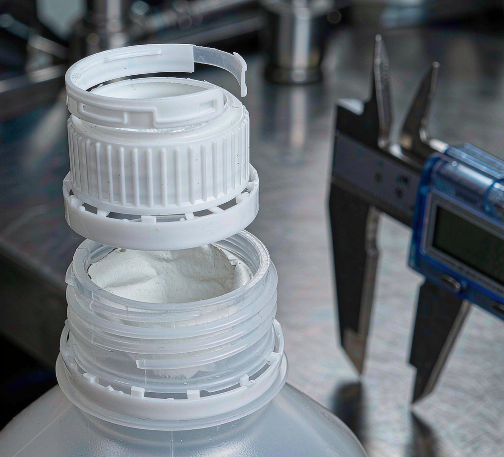 Pharmaceutical packaging plastic bottles — white HDPE pill bottle with child-resistant cap, amber bottle and clear PET narrow-neck bottle — with caps beside them
