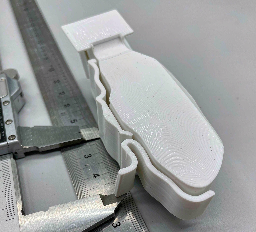 Close-up of a molded polypropylene living hinge web and snap-fit arm beside calipers on an inspection bench