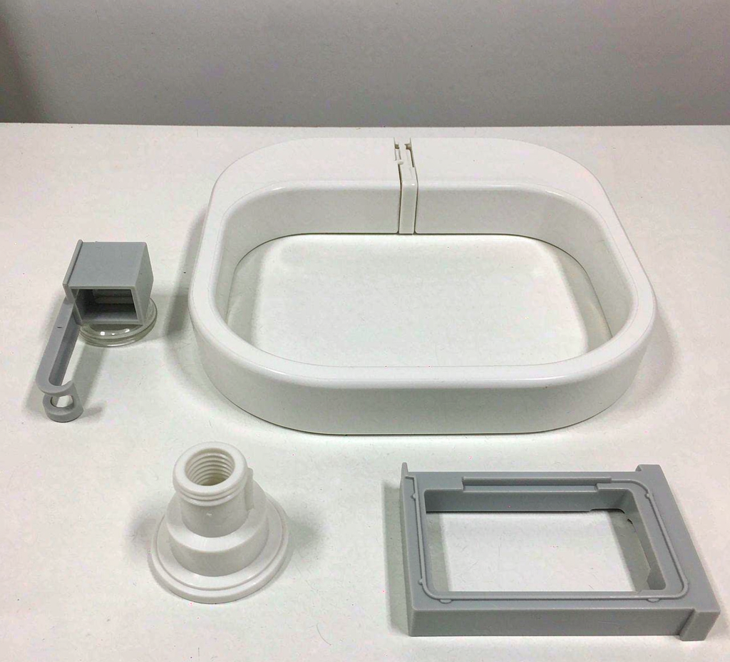 Custom injection-molded polypropylene parts — equipment housing with living hinge, snap-fit clip, connector fitting and industrial bracket — on a factory surface