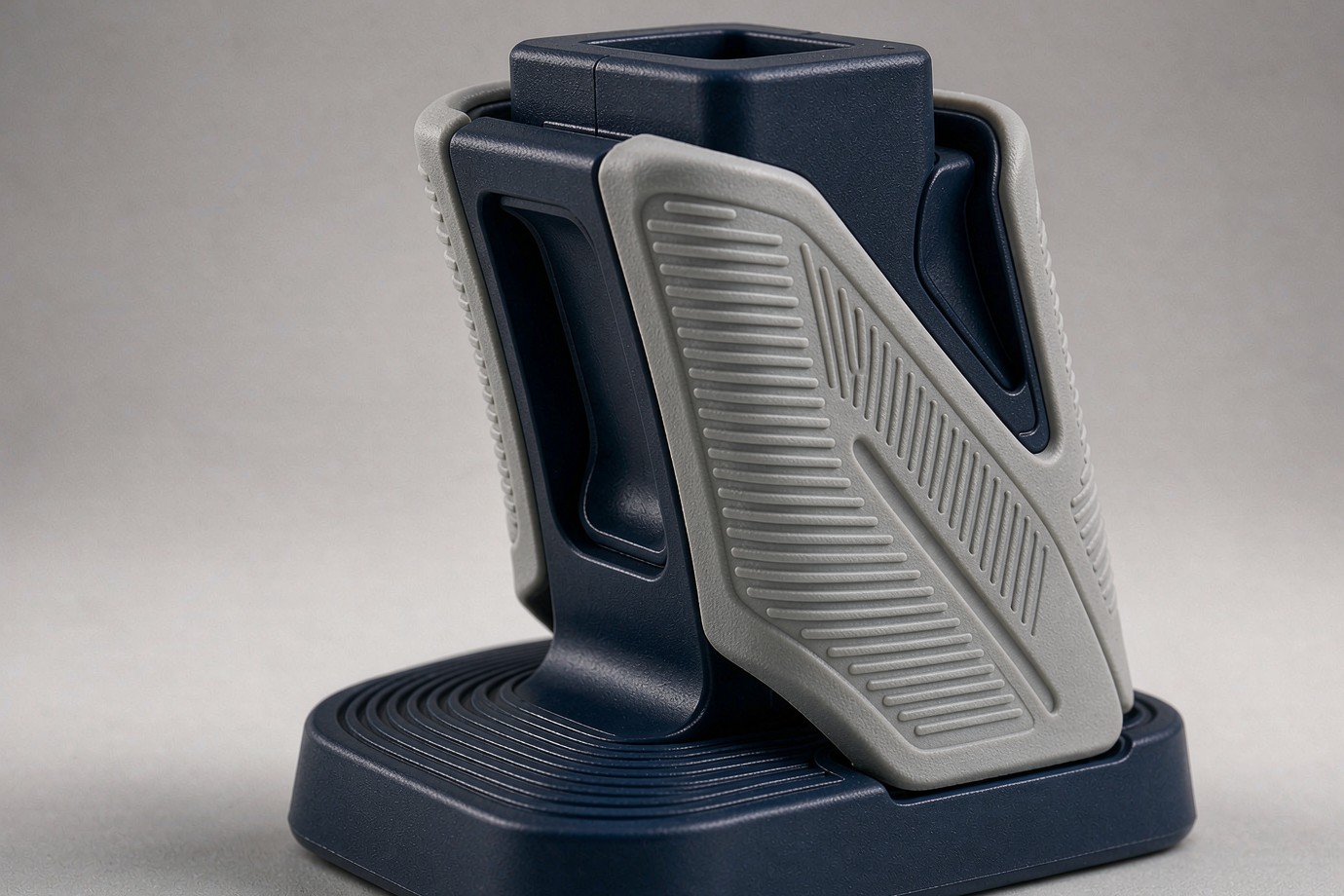 Prototype overmolded part with a rigid dark navy plastic substrate and a grey soft-touch TPE grip section with a textured surface