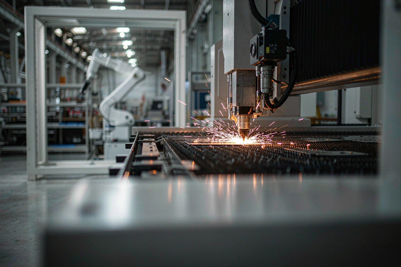 Illustrative — fiber laser cutting machine cutting a steel sheet with bright sparks in a bright clean factory