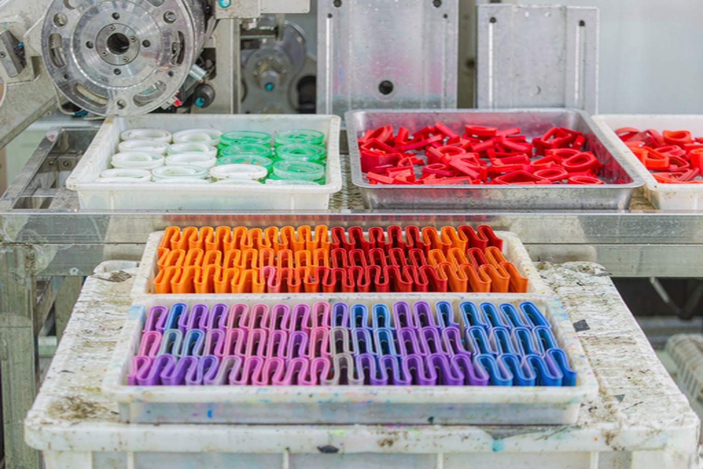 Illustrative — trays of freshly molded colourful silicone gaskets, membranes and caps on a clean manufacturing bench