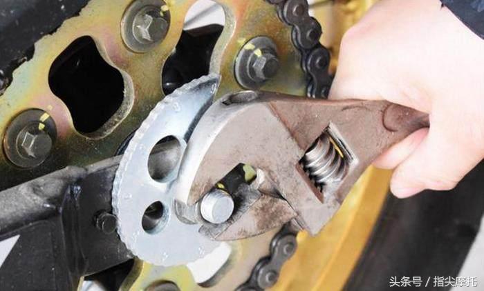 Using wrench to adjust motorcycle chain tension