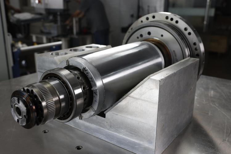 CNC cylindrical grinder finishing a precision titanium shaft for aerospace use